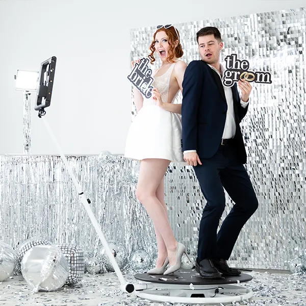 Wedding guests throwing confetti while standing on a 360 video booth platform.