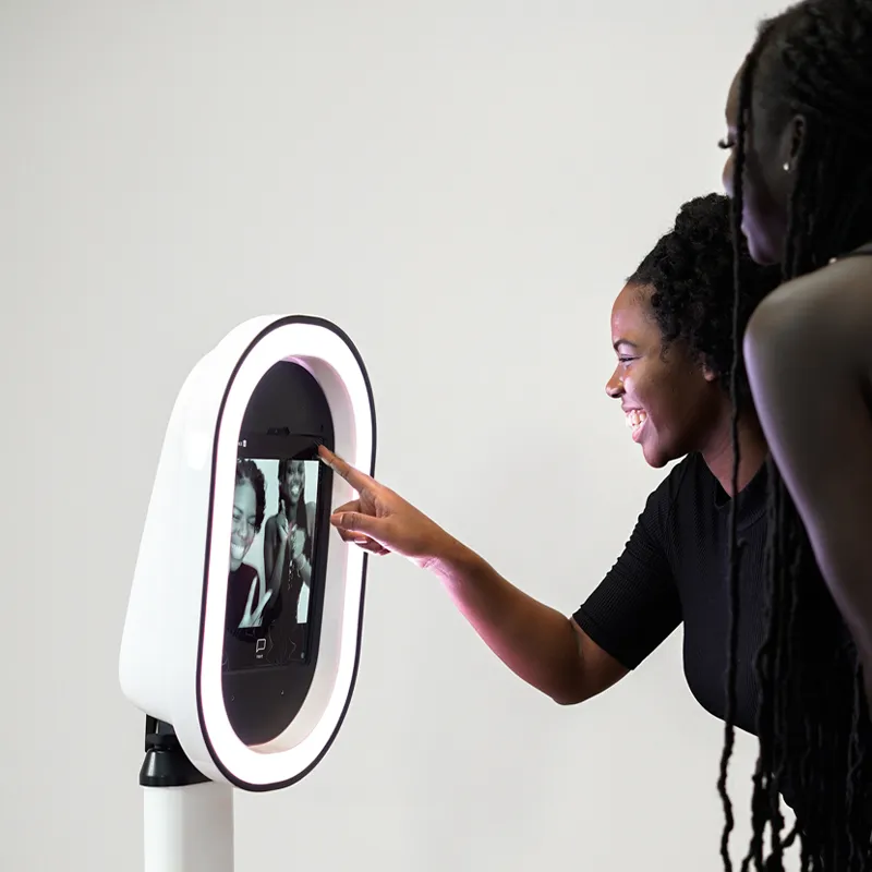 Sleek white iPad photo booth with LED ring light at a modern event.